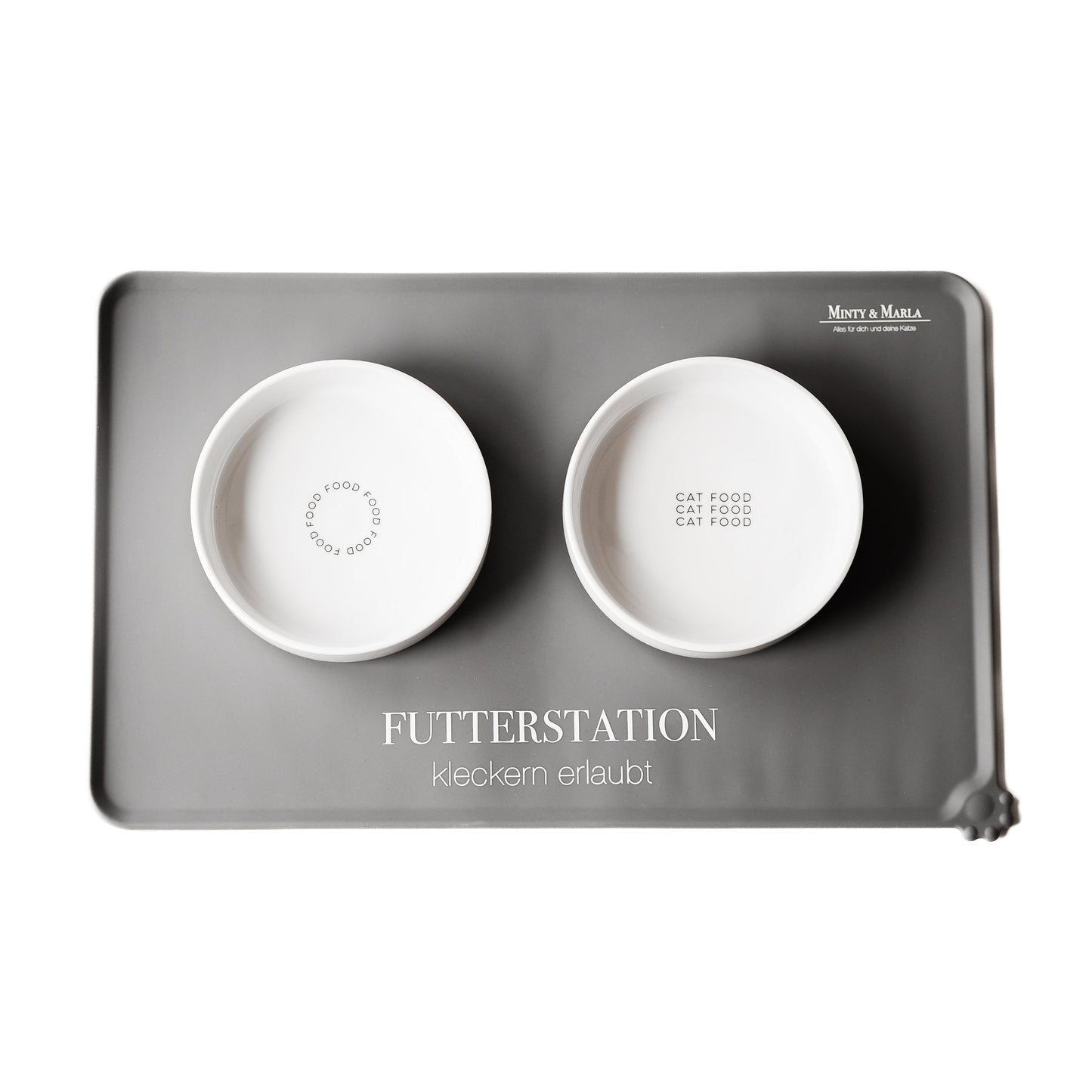 Beige Napfunterlage für Katzen aus Silikon auf der zwei große weiße Keramiknäpfe stehen mit dem verschiedenen Aufdrucken.