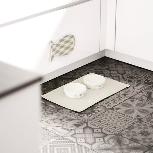 Schöner Futterplatz für Katzen bestehend aus einer Napfunterlage, Katzennäpfen und einer Schleckmatte zur Beschäftigung.