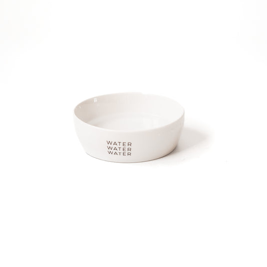 Ein weißer Keramiknapf für Katzen mit dem Aufdruck "water water water" vor einem weißen Hintergrund.