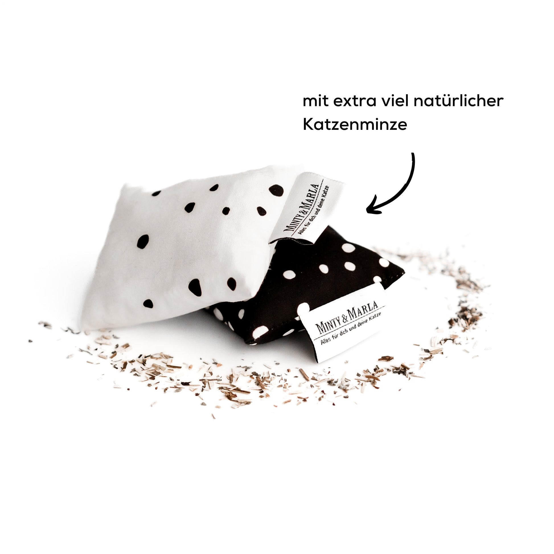 Zwei Katzenminzekissen liegen übereinander. Die Kissen sind schwarz und weiß mit Punkten und dienen als Katzenspielzeug.