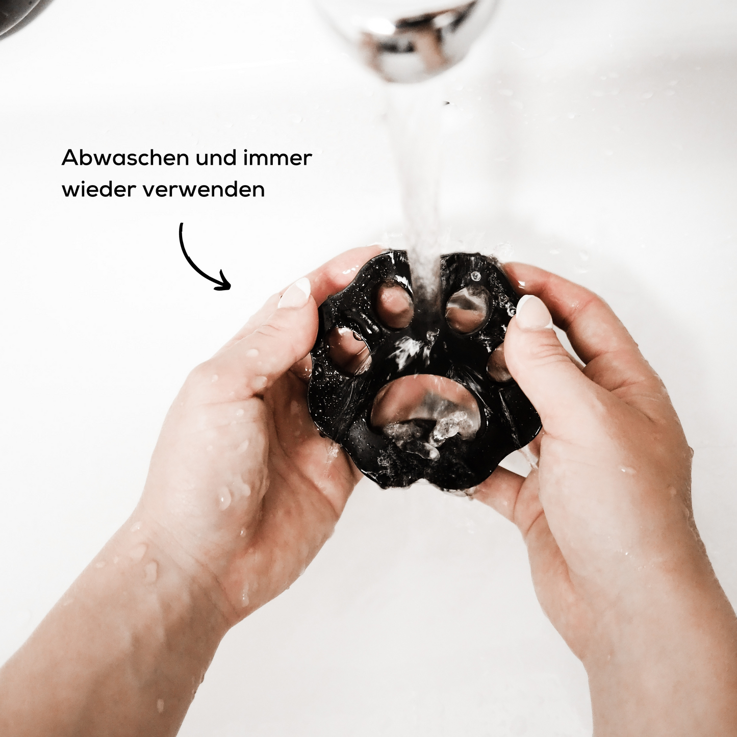 Wiederverwendbarer Haarentferner zum Entfernen von Tierhaaren wird unter dem Wasserhahn abgewaschen.