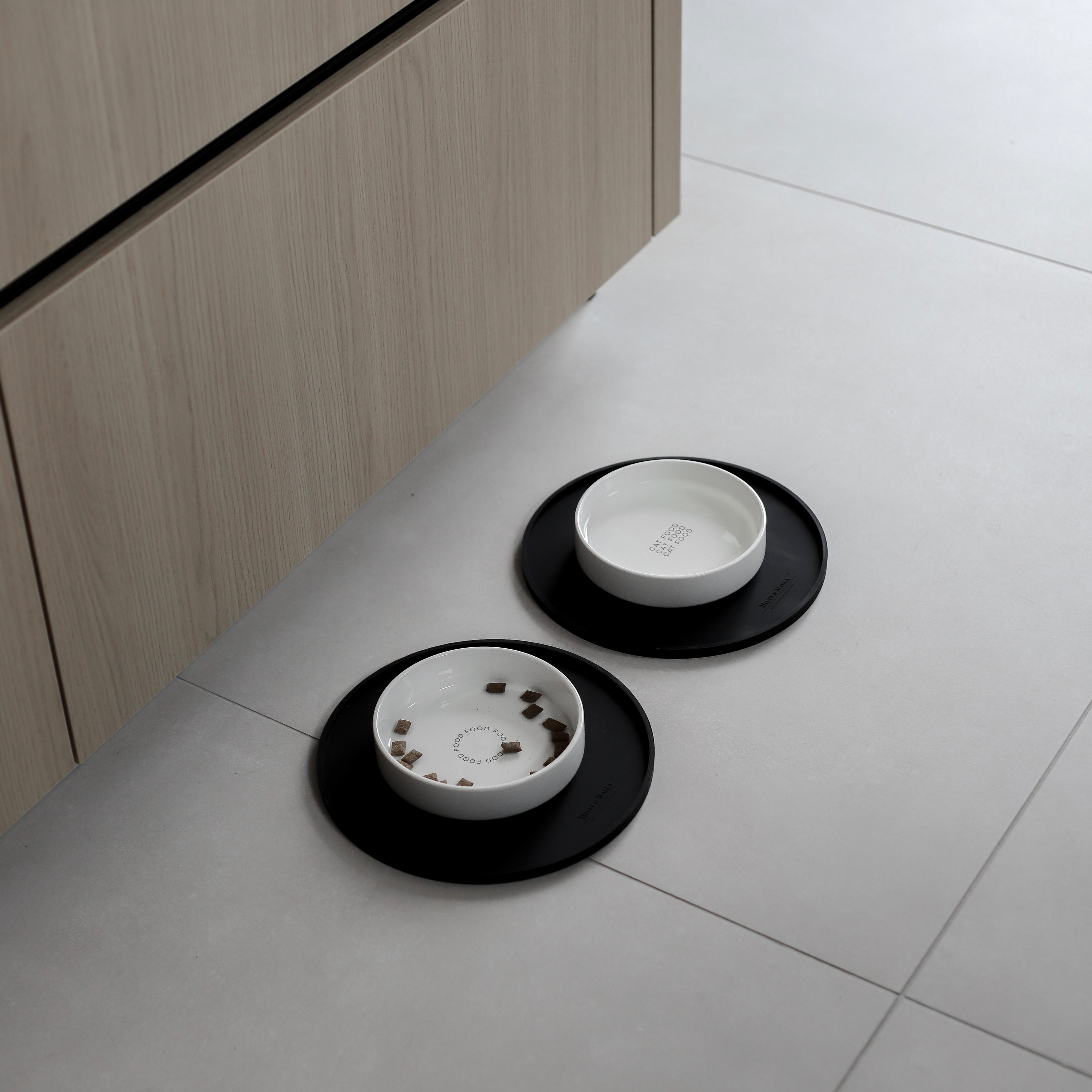 In einer modernen Küche stehen zwei stilvolle Futterplätze für Katzen mit weißen Keramiknäpfen