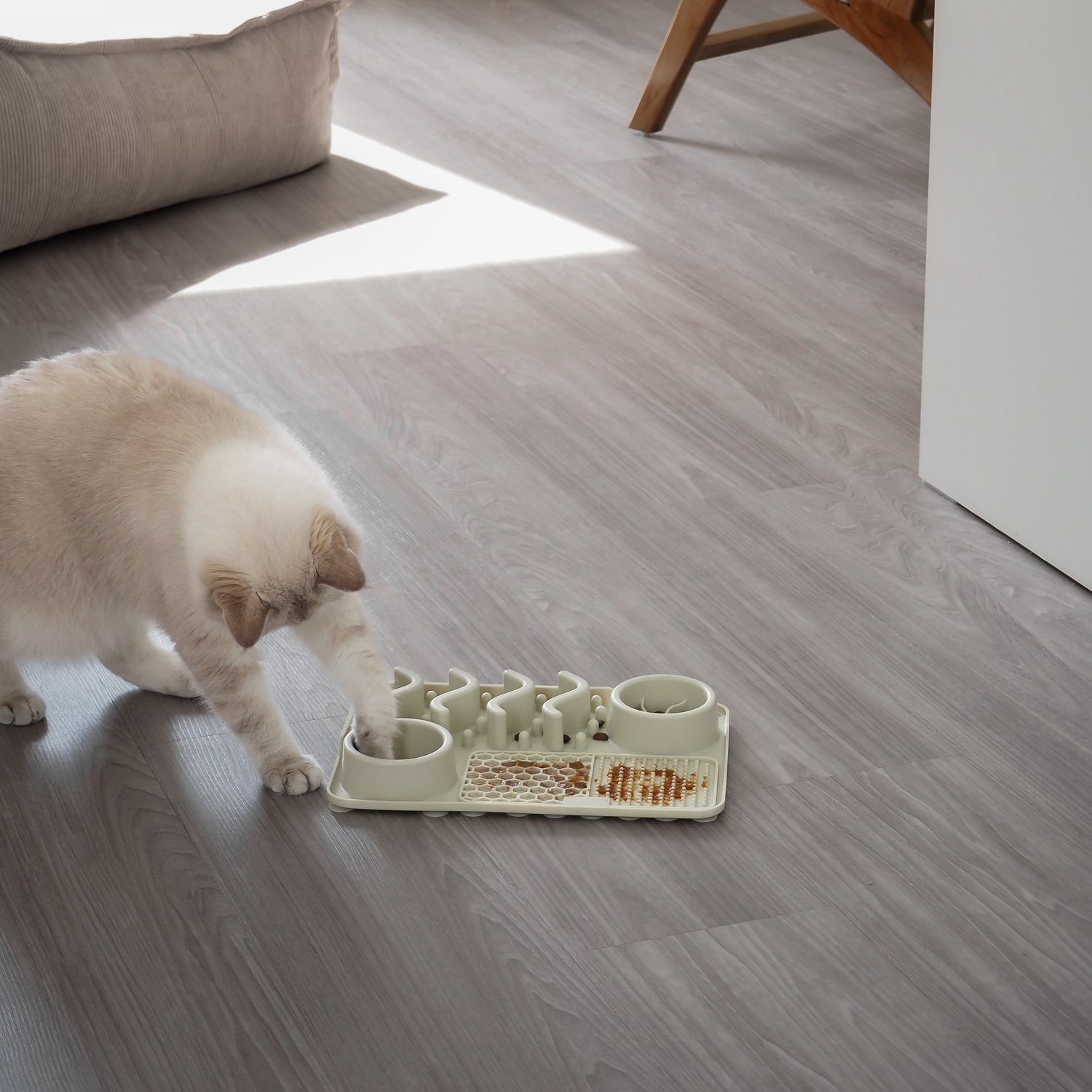Ein beiges Fummelbrett für Katzen liegt vor einem weißen Hintergrund. Auf dem Fummelbrett liegt Katzenfutter zur Beschäftigung von Katzen. 