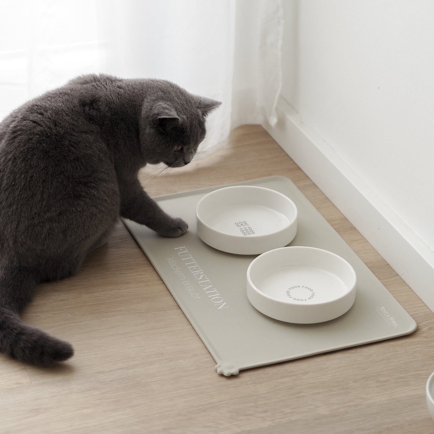 Artgerechter Futterplatz für Katzen bestehend aus einer beigen Napfunterlage und zwei flachen Näpfen aus Keramik.